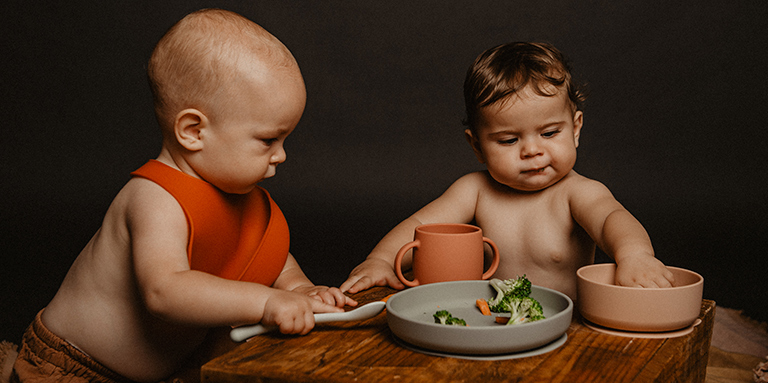 Dos bebés comiendo con las manos